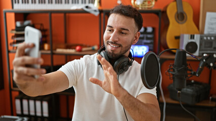 Young arab man musician wearing headphones having video call at music studio