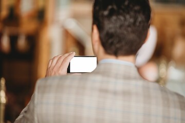 Man holding a smartphone to take a picture with copy space on the screen, shot from back