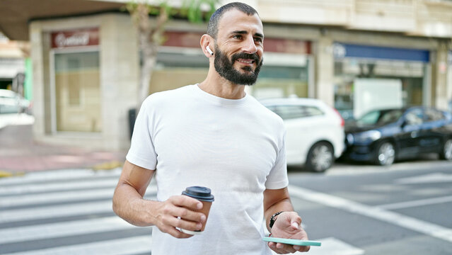Young hispanic man drinking coffee having free hands call at street