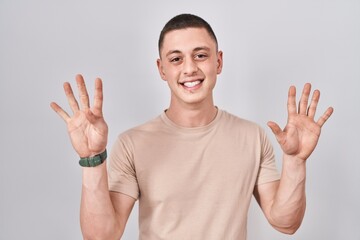 Young man standing over isolated background showing and pointing up with fingers number nine while smiling confident and happy.