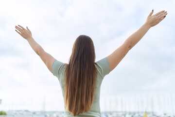Young beautiful woman standing with arms open at seaside