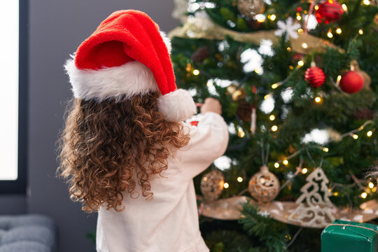 Adorable blonde toddler decorating christmas tree at home