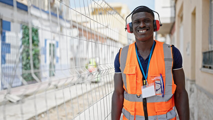 African american man builder smiling confident wearing headphones at construction place