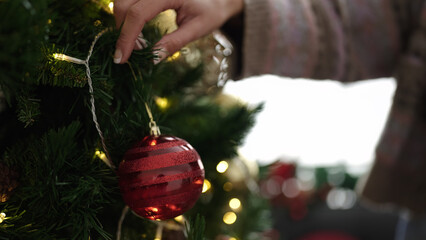 Young blonde woman decorating christmas tree at home