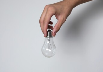 Hand holds light bulb on white background. Demonstrates the problem of unconscious consumption