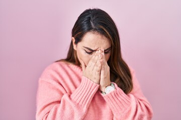 Young hispanic woman standing over pink background with sad expression covering face with hands while crying. depression concept.