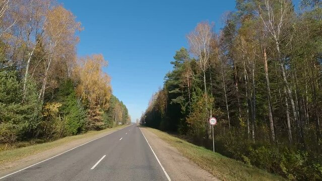 The car drives along the road on a autumn day. Highways, roadside and road line markings.