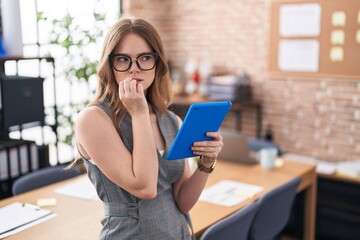 Caucasian woman working at the office wearing glasses looking stressed and nervous with hands on...