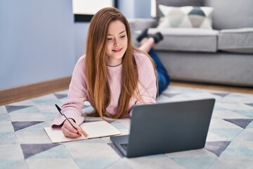 Young caucasian woman lying on floor studying at home