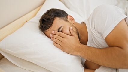 Fototapeta na wymiar Young hispanic man lying on bed crying at bedroom