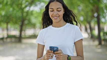 African american woman using smartphone walking at park