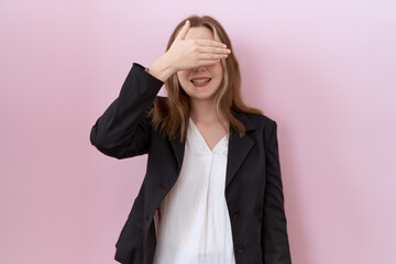 Young caucasian business woman wearing black jacket smiling and laughing with hand on face covering eyes for surprise. blind concept.