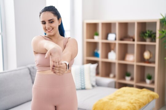 Young caucasian woman smiling confident stretching arm at home