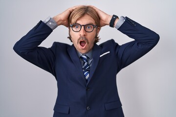 Caucasian man with mustache wearing business clothes crazy and scared with hands on head, afraid and surprised of shock with open mouth