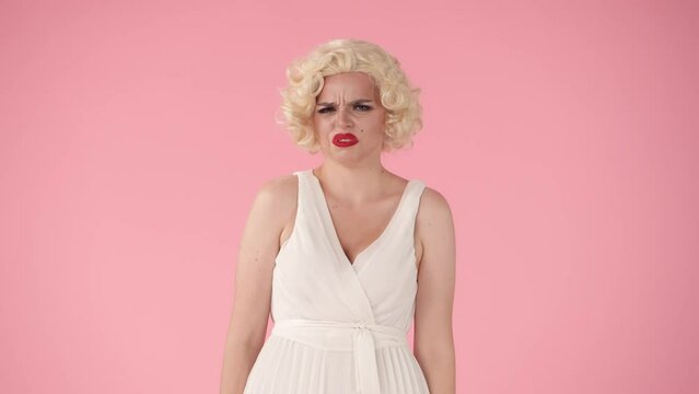 The woman is disgusted by an unpleasant odor, or taste, covers her mouth with her hand, waves it away. A woman in the image of is isolated on pink.