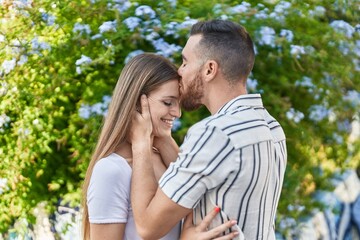 Fototapeta premium Man and woman couple hugging each other kissing at park
