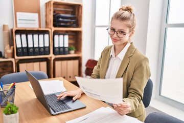 Young blonde woman business worker using laptop reading document at office