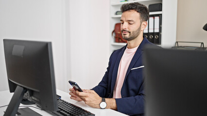 Young hispanic man business worker using computer and smartphone at office