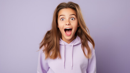 Obraz na płótnie Canvas Happy Surprised and Excited, Opening Eyes and Mouth, Smiling Enchanted Girl Wearing Bright Lavender Clothes on a Solid Lavender Background