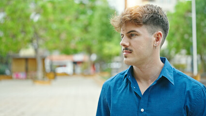 Young hispanic man looking to the side with serious expression at park