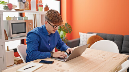 Young hispanic man using laptop sitting on table at dinning room