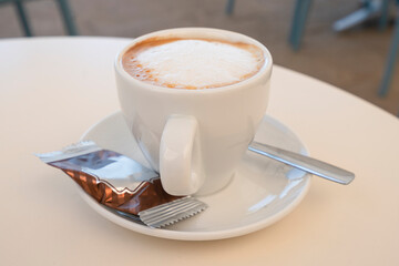 White cup of delicious cappuccino on table