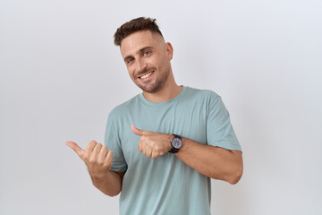 Hispanic man with beard standing over white background pointing to the back behind with hand and...
