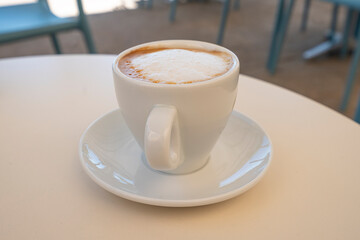 White cup of delicious cappuccino on table