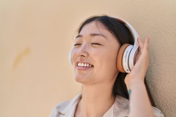 Chinese woman smiling confident listening to music over white isolated background