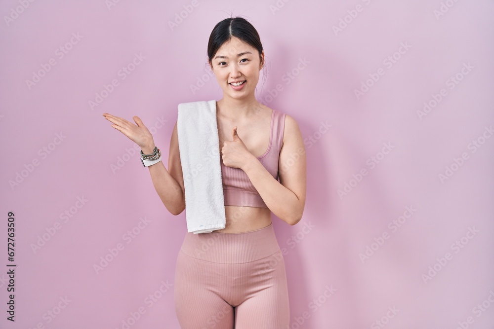 Wall mural chinese young woman wearing sportswear and towel showing palm hand and doing ok gesture with thumbs 