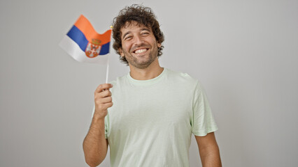 Young hispanic man smiling confident holding serbian flag over isolated white background