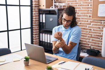 Young hispanic man business worker suffering for wrist pain working at office