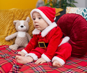 Fototapeta na wymiar Adorable caucasian baby wearing christmas costume sitting on sofa at home
