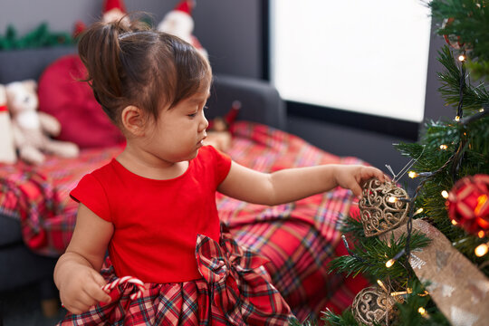 Adorable chinese girl decorating christmas tree standing at home