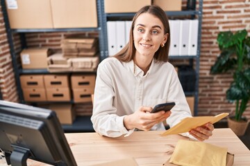 Young caucasian woman ecommerce business worker using smartphone holding package at office