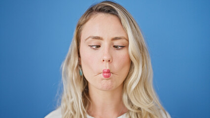 Young blonde woman smiling confident doing funny gesture with mouth over isolated blue background