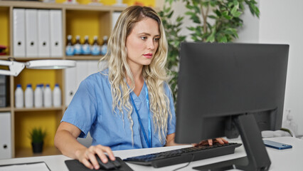 Fototapeta na wymiar Young blonde woman doctor using computer working at clinic