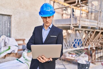 Young man architect using laptop at street