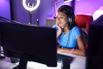 Brunette young woman playing video games thinking looking tired and bored with depression problems with crossed arms.