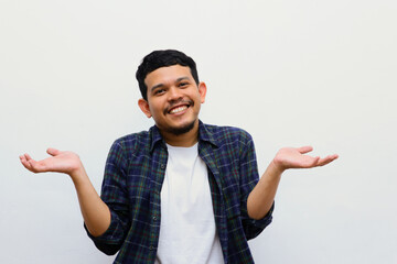 Young adult asian man raised arms and looking at camera with smiling face. studio shot, isolated on light grey background. - obrazy, fototapety, plakaty