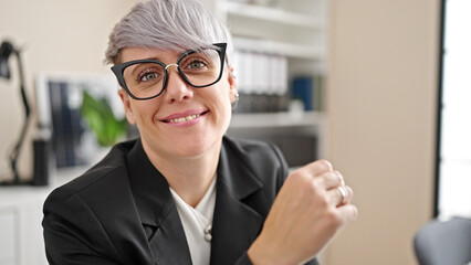 Young woman business worker sitting on table smiling at office