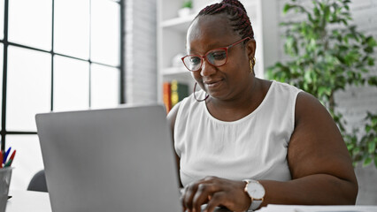 Focused african american woman worker excelling in business. working diligently at her laptop, this...