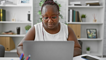 Focused african american woman worker excelling in business. working diligently at her laptop, this boss lady embodies success and professionalism in her office.