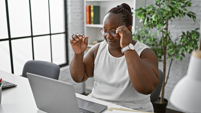 Confident african american woman, a happy business worker using laptop at office wearing glasses