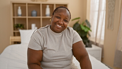 Fototapeta premium Radiant african american woman enjoying a relaxing morning, confidently smiling on her cozy bedroom bed.