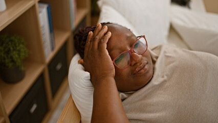 Exhausted african american woman, stressed out with her daily lifestyle, lying in bed worried and...