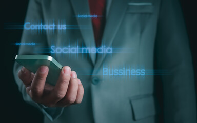 Fototapeta na wymiar Close-up shot of businessman holding smartphone on dark background Represents business communication concepts.