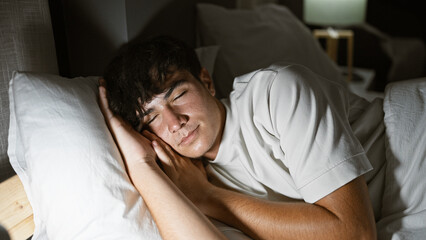 Exhausted young hispanic man finds comfort in a bright morning sleep, lying undisturbed in his cozy bedroom, surrendering to the soft embrace of his bed and pillow, in a relaxed indoor portrait. - obrazy, fototapety, plakaty