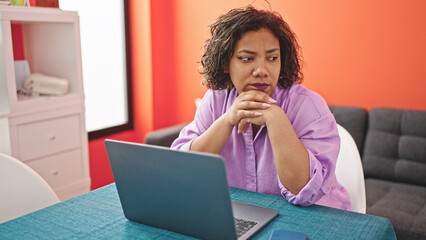 Young beautiful latin woman using laptop sitting on table thinking at dinning room