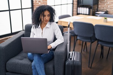 Young hispanic woman business worker using laptop waiting for travel at office